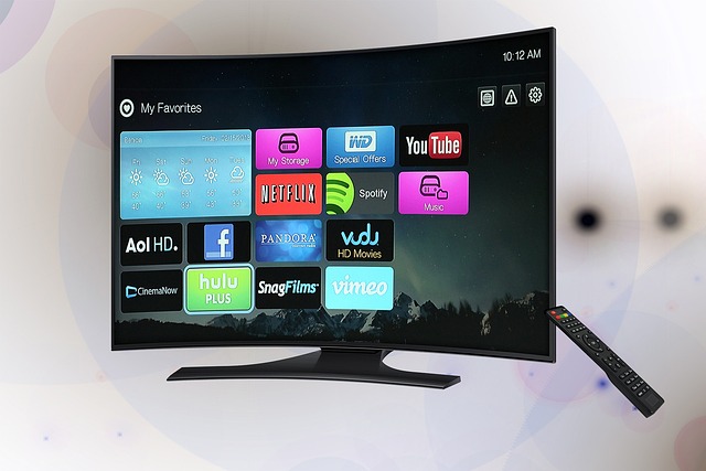 Curved flat-screen smart TV on a stand showing colorful streaming app icons; a black remote rests to the right.