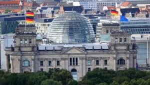 Berlin's Reichstag building with its glass dome and flags atop, set against a city skyline.
