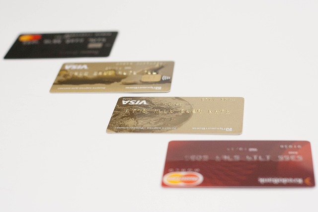 Five credit cards arranged diagonally on a white surface, showing various colors including black, gold, and red.