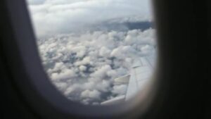 View from an airplane window showing white clouds and part of the wing.